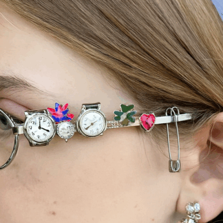 petites lunettes ovales argentées avec bijoux et montres sur les branches.